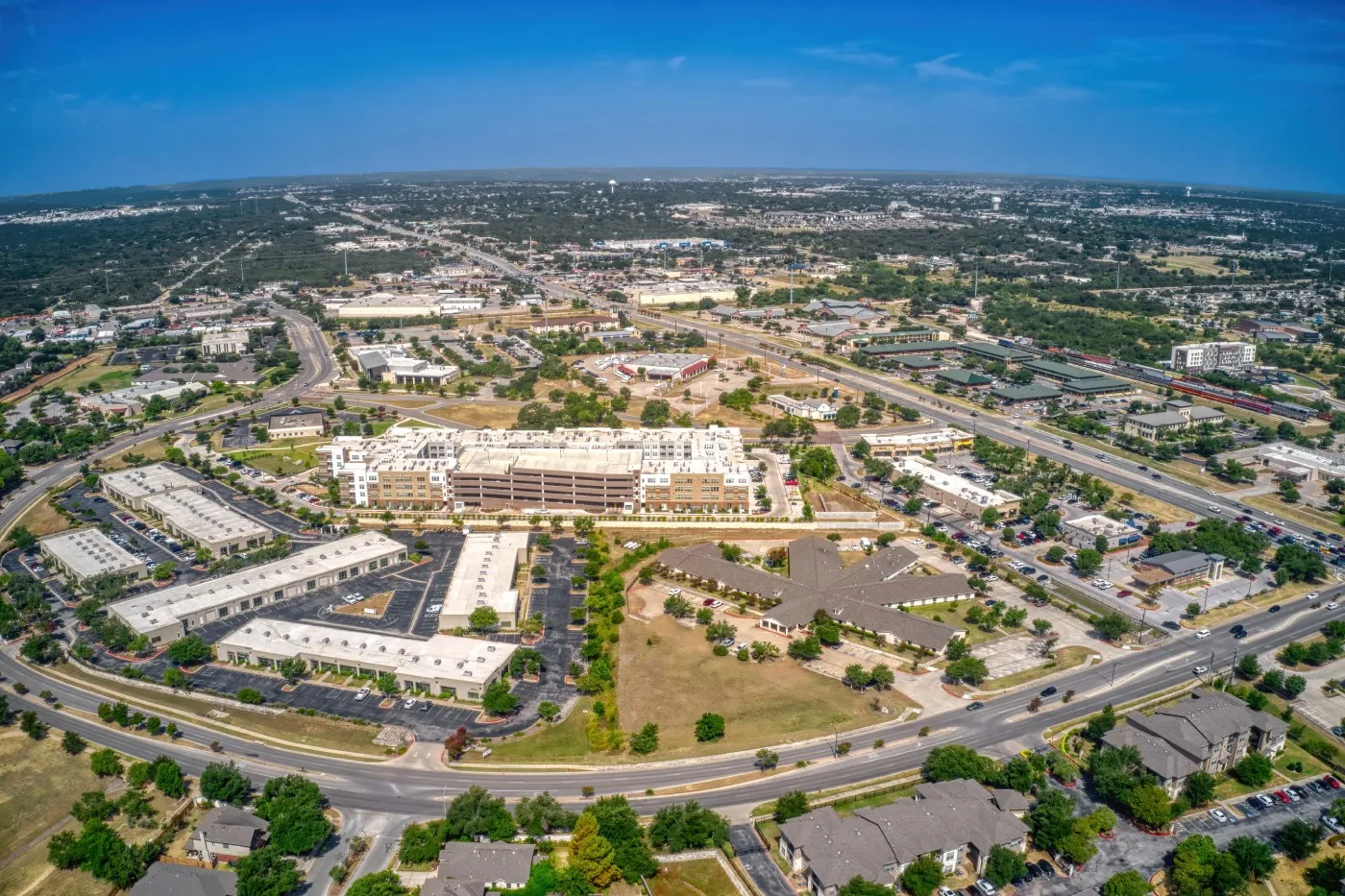 Aerial view of a suburban town center with commercial buildings, roads, and neighborhoods.