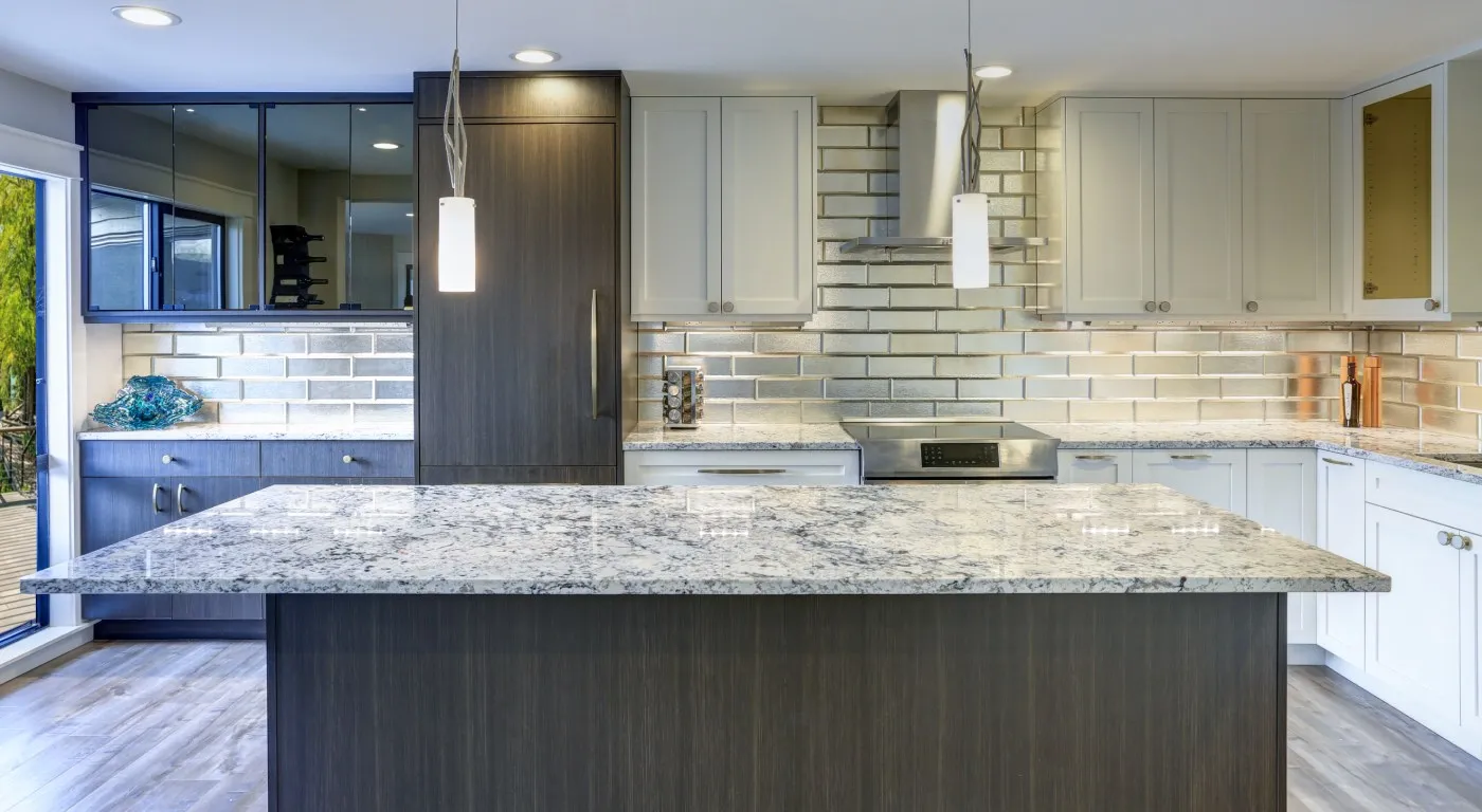 Modern kitchen with a large quartzite island featuring a gray and white pattern, dark wood base, white upper cabinets, mirrored tile backsplash, stainless steel range hood, pendant lighting, and a mix of dark and white cabinetry.
