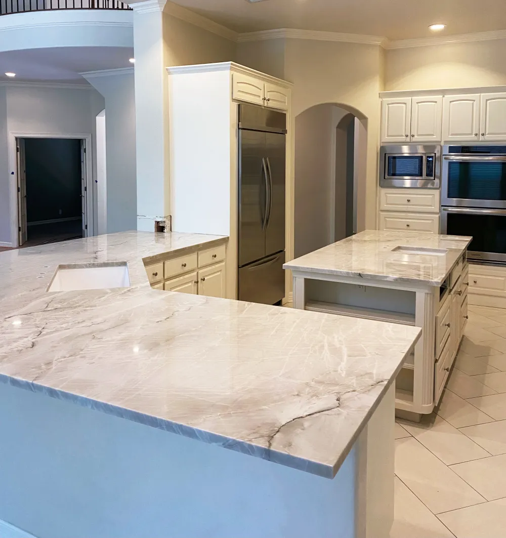Modern kitchen with white quartzite countertops, island, stainless steel appliances, and cream cabinetry.