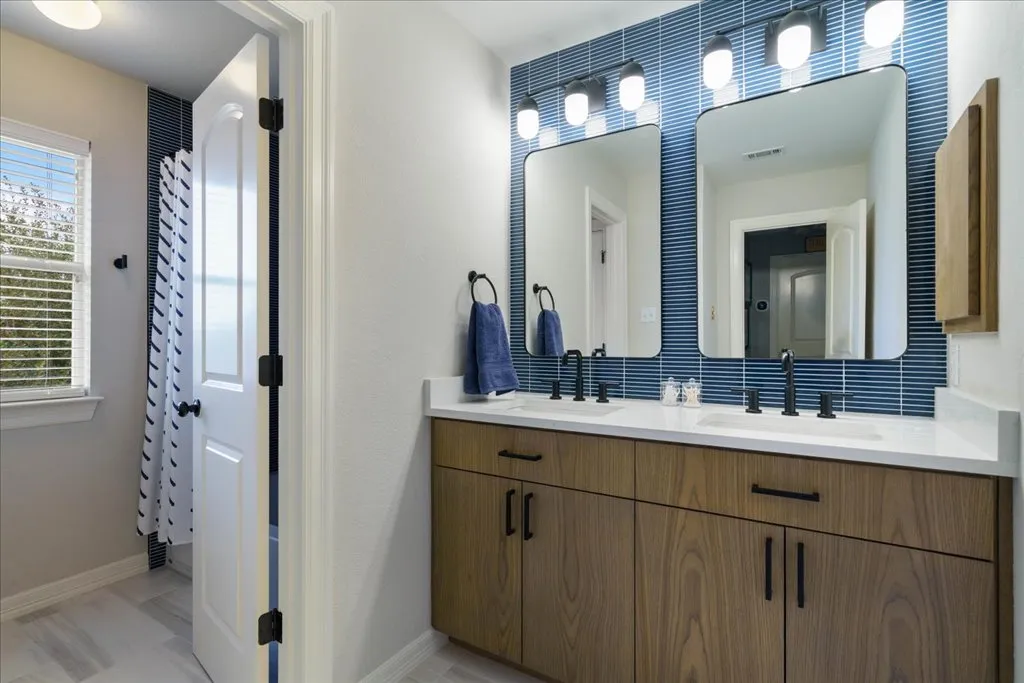 Wood vanity with white quartz double-sink countertop and blue tile backsplash