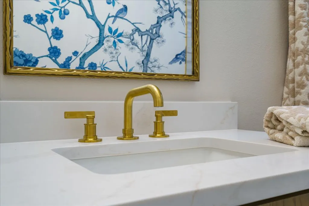Close-up of white quartz bathroom vanity countertop with gold faucet fixtures
