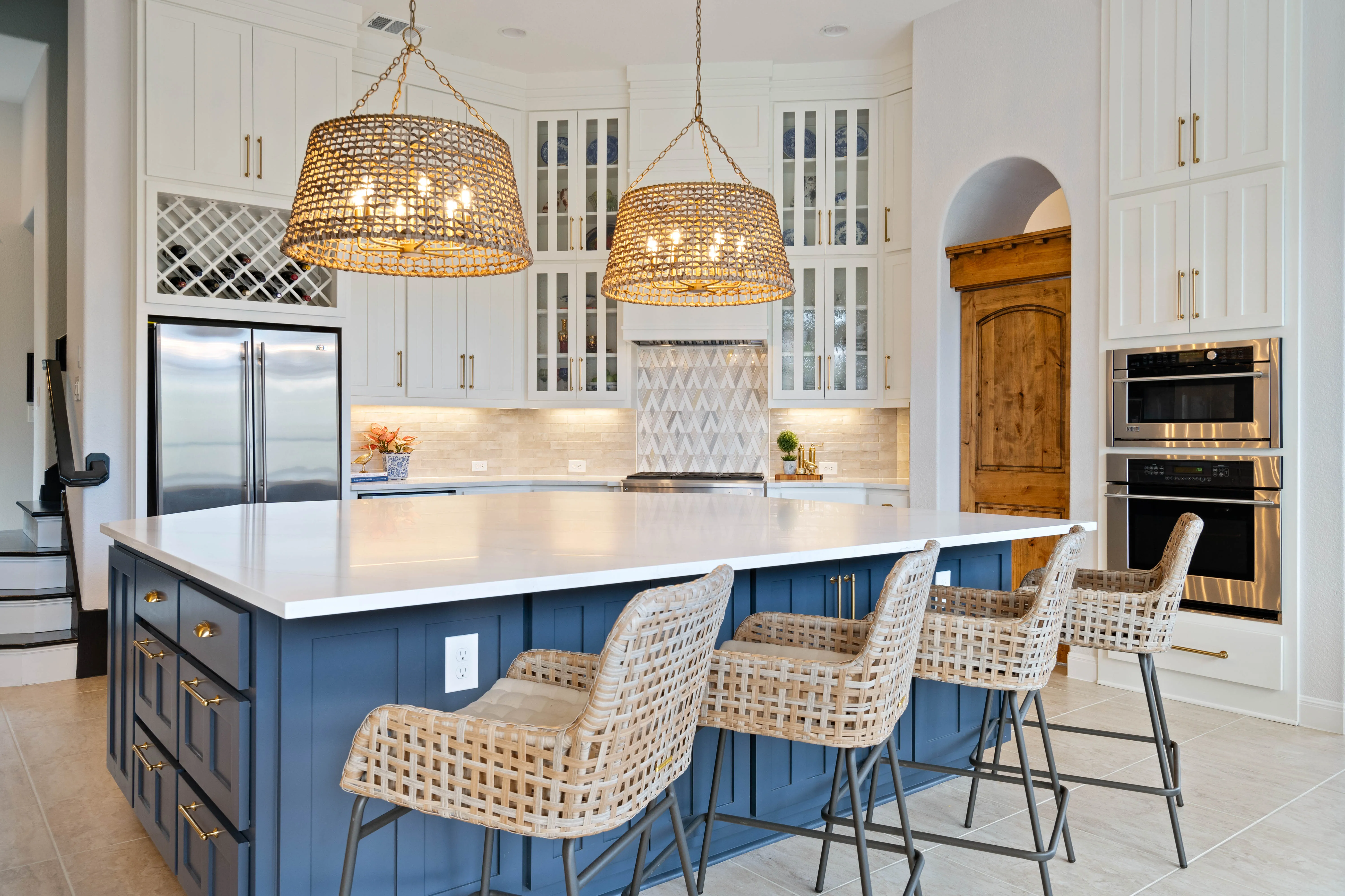 Kitchen with navy blue island, white quartz countertop, and woven counter stools