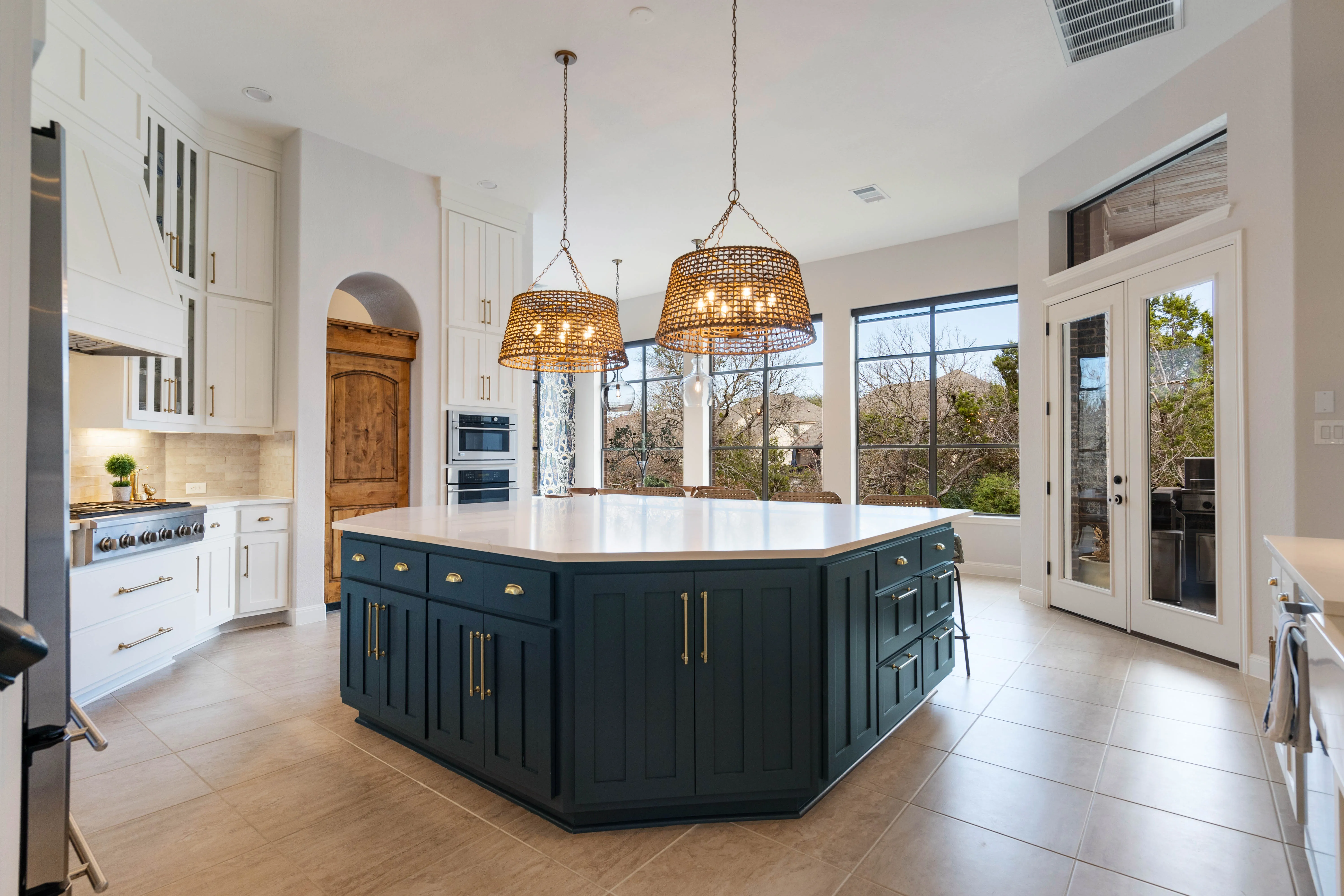 Navy blue kitchen island with white quartz countertop and woven pendant lights