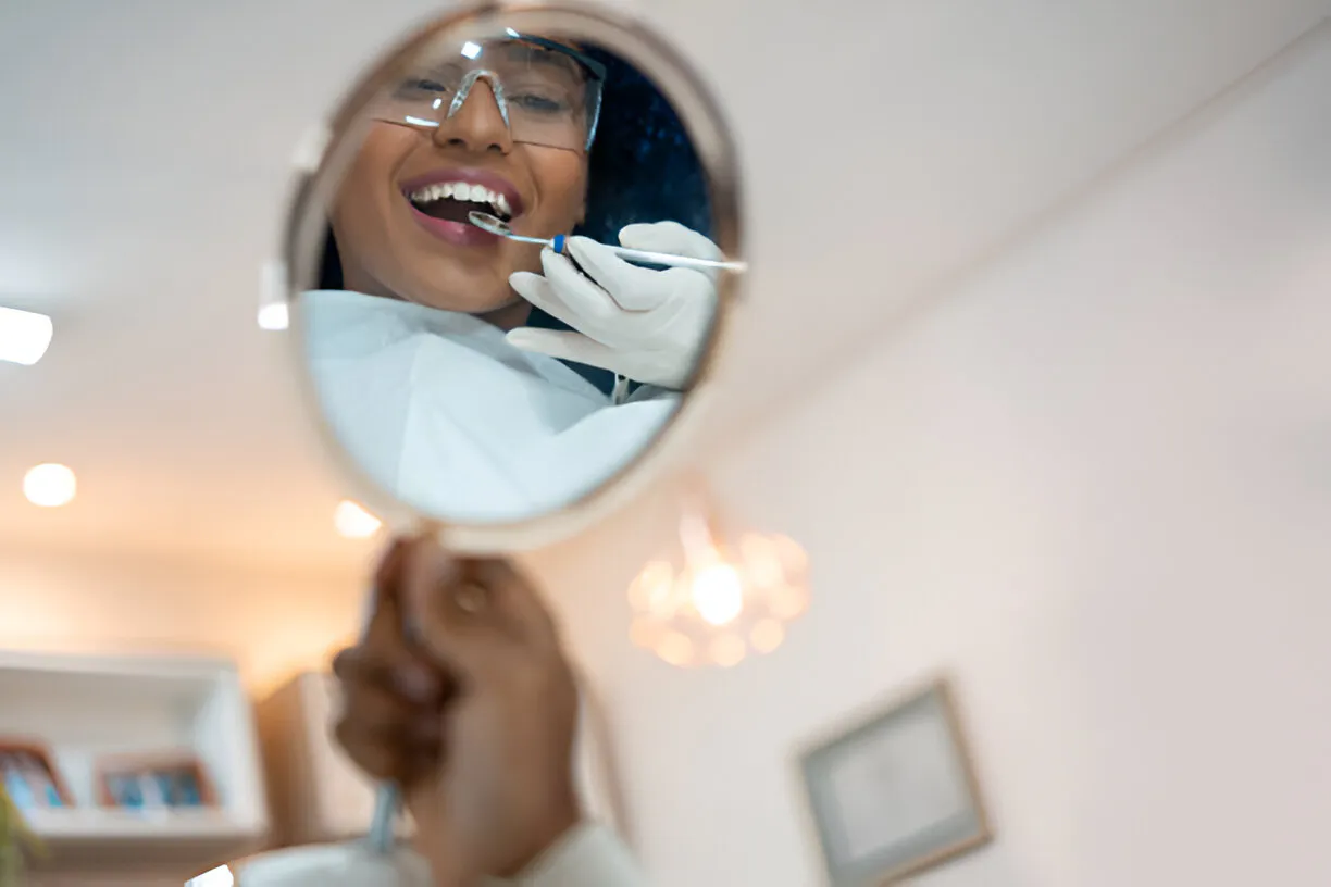 Dental mirror reflecting a smiling patient during a checkup