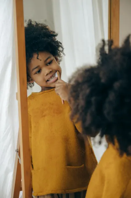 Child looking at their teeth in a mirror