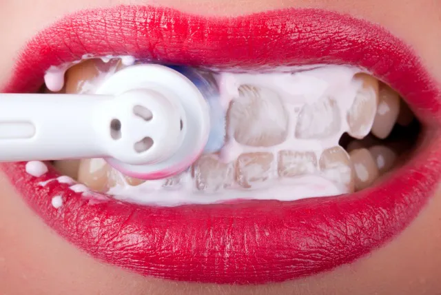 Close-up of an electric toothbrush cleaning teeth along the gumline