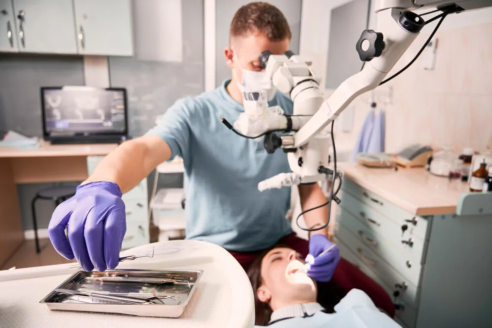 Endodontist performing a root canal using a dental microscope