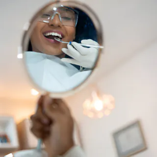 Round dental mirror reflecting a smiling patient during a checkup