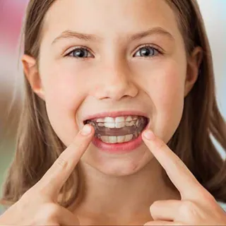 Girl pointing to her teeth while wearing a clear aligner
