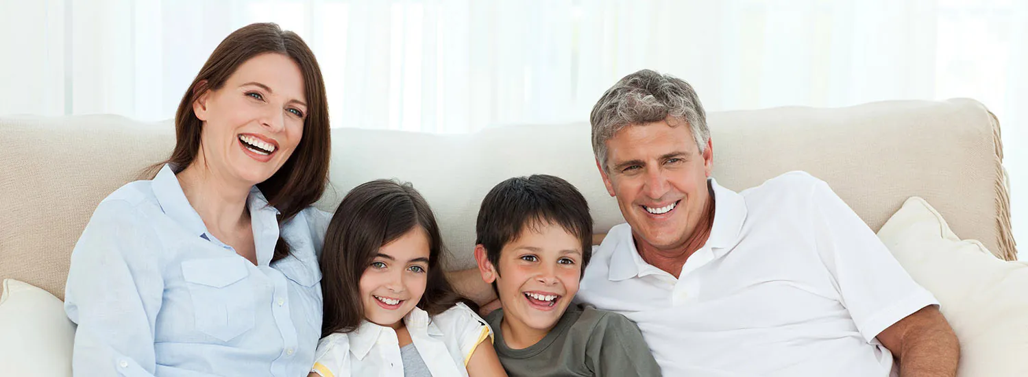 A family of four smiling together on a couch