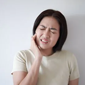 Woman wincing and holding her cheek in pain