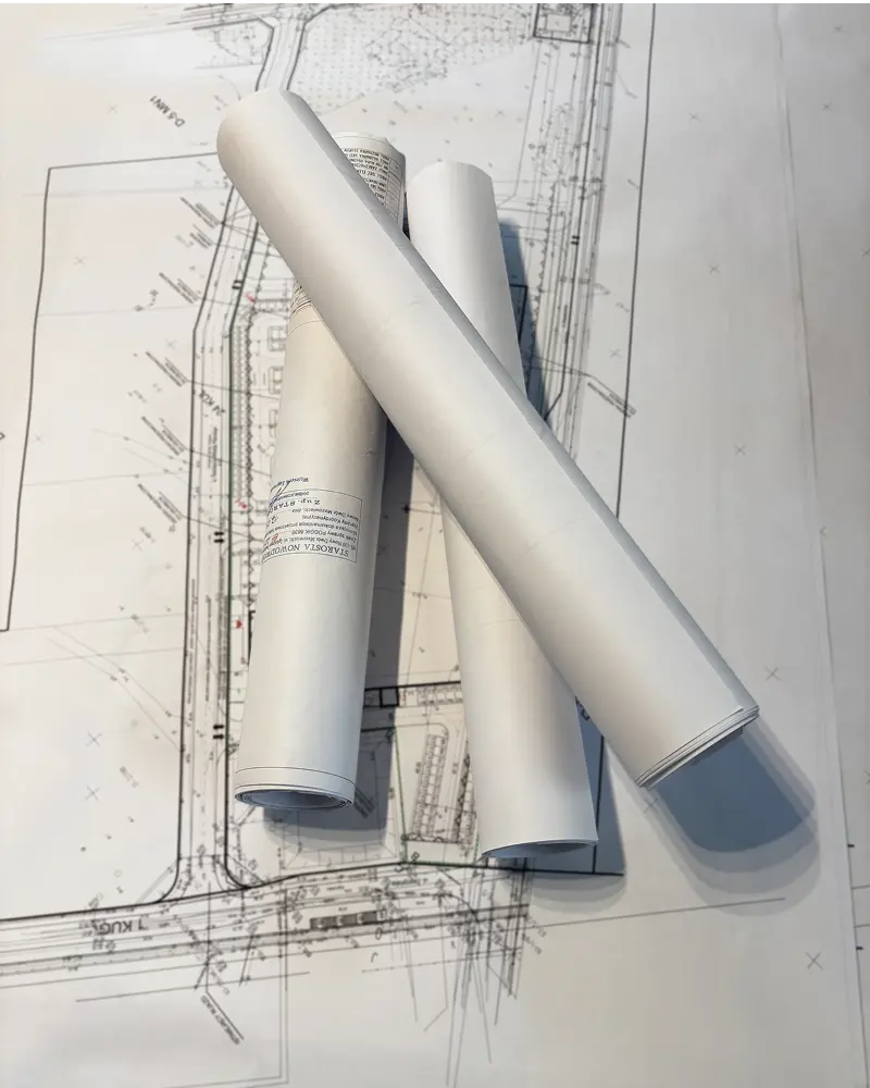 Zdjęcie przedstawia zwinięte rulony projektów drogowych.