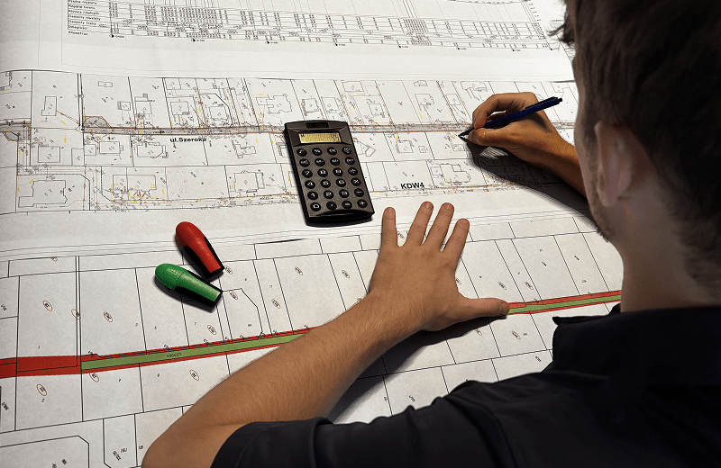 Zdjęcie przedstawiające projektanta wpisującego pomiary w koncepcję inwestycji drogowej.