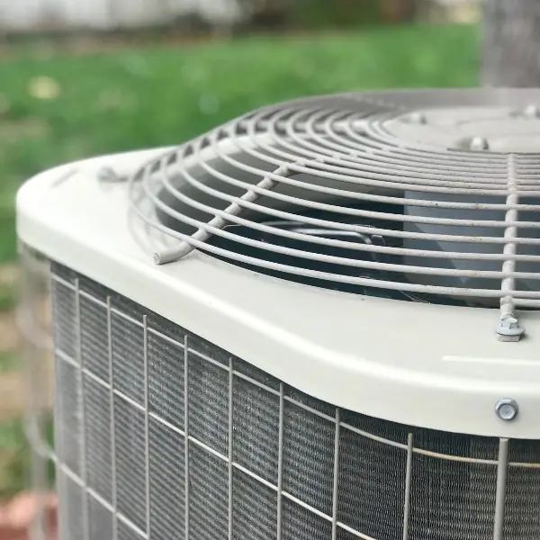 Close-up of an air conditioning unit's top with a metal grille and fan.