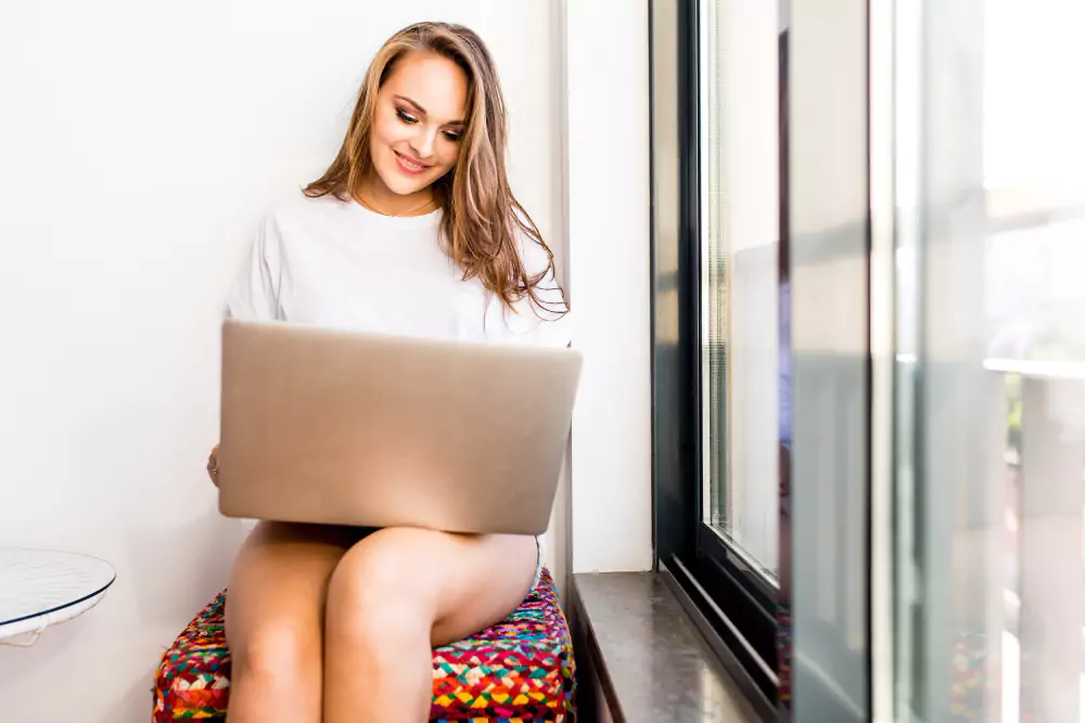 Jonge vrouw zit thuis op een stoel met een laptop