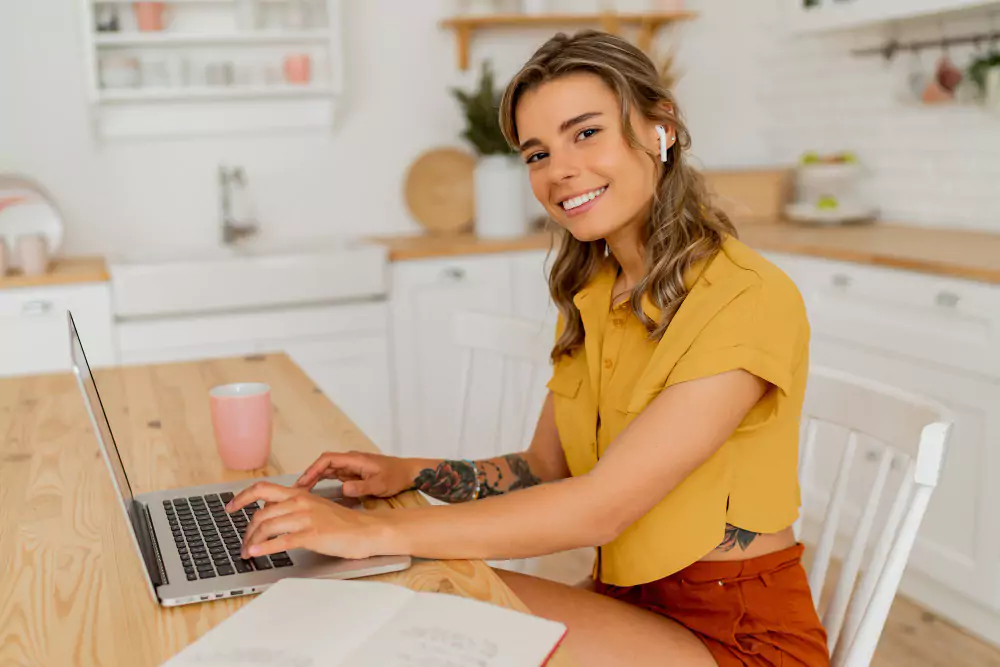 Mooie vrouw die thuis een laptop gebruikt en aantekeningen maakt