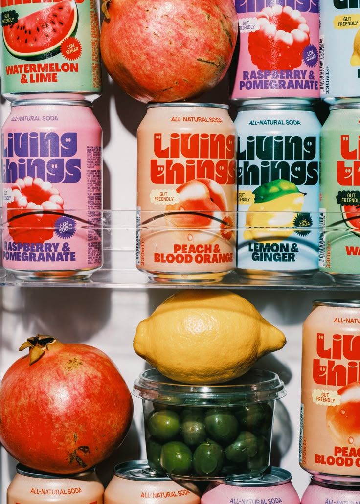 Canettes Living Things dans un réfrigérateur, entourées de fruits