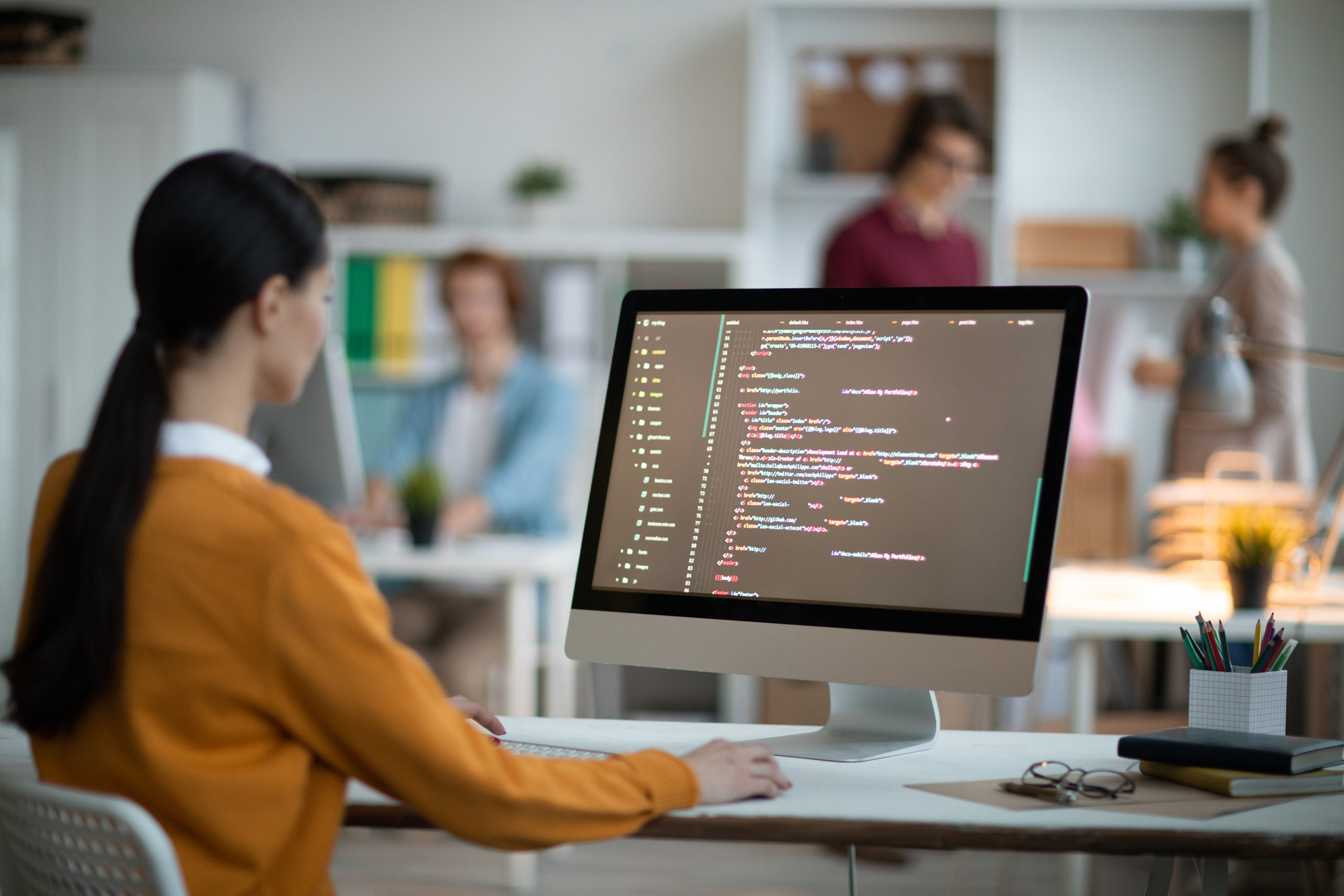 Analista programando en una computadora con varias ventanas y líneas de código, representando desarrollo de software e implementación de estrategias digitales para empresas Hiweb