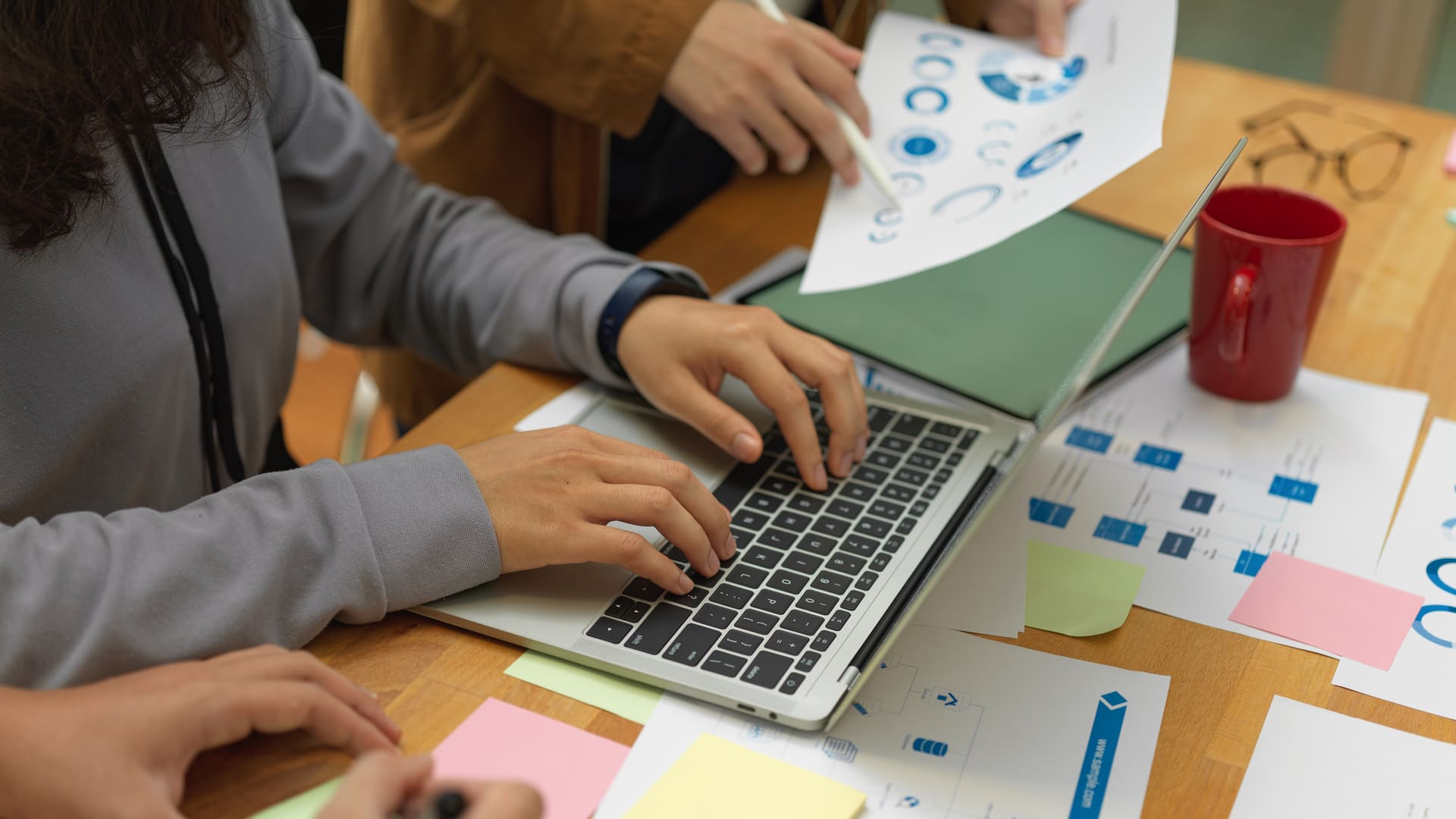 Equipo de marketing colaborando en proyectos digitales con laptop, documentos de planificación y materiales de estrategia creativa Hiweb