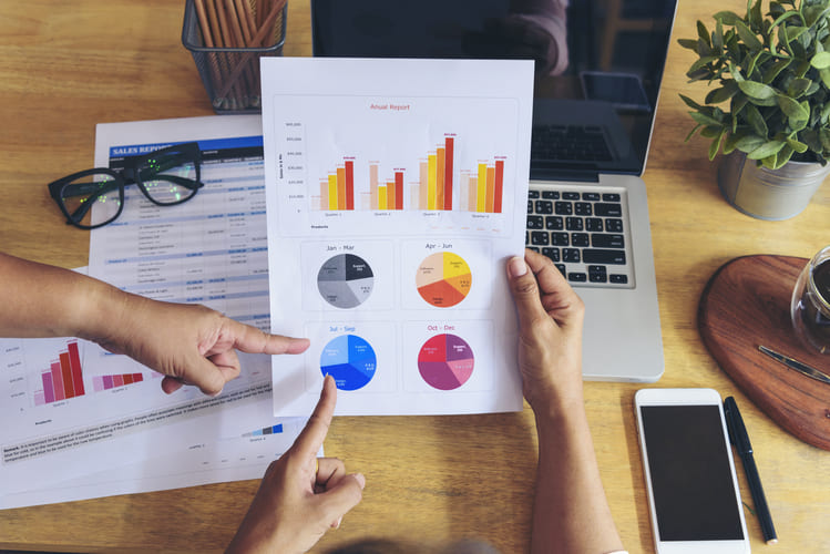 Profesional analizando reportes empresariales y gráficos financieros en laptop para apoyar decisiones de marketing basadas en datos Hiweb