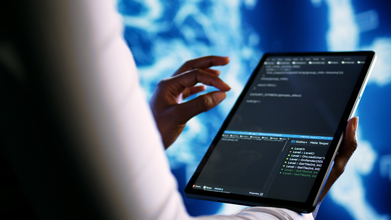 Profesional utilizando una tablet con código de programación e interfaz de desarrollo de software en un entorno tecnológico Hiweb