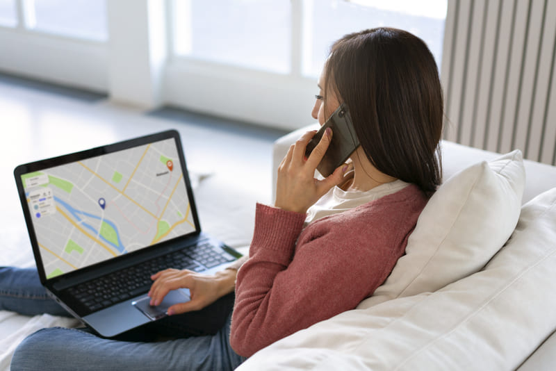 Person searching for real estate locations online using a laptop and phone while exploring property options Hiweb