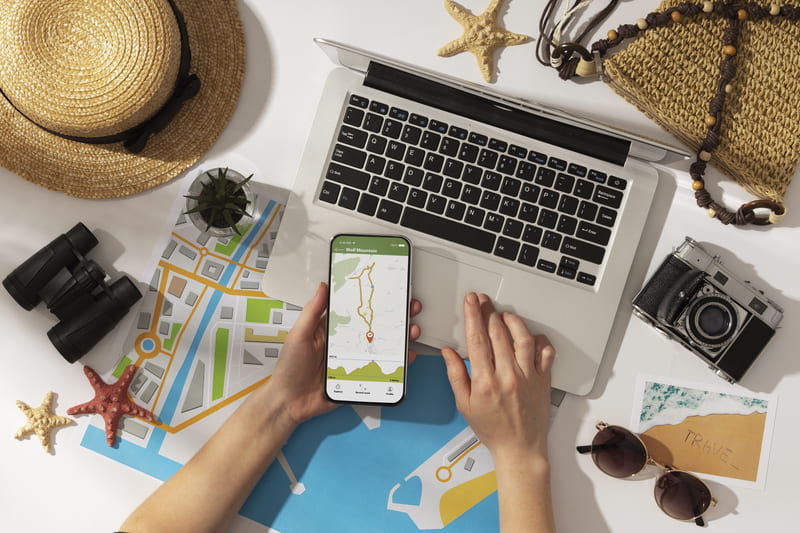 Espacio de planificación de viajes con laptop, mapa, smartphone y equipo fotográfico representando estrategias digitales de turismo Hiweb