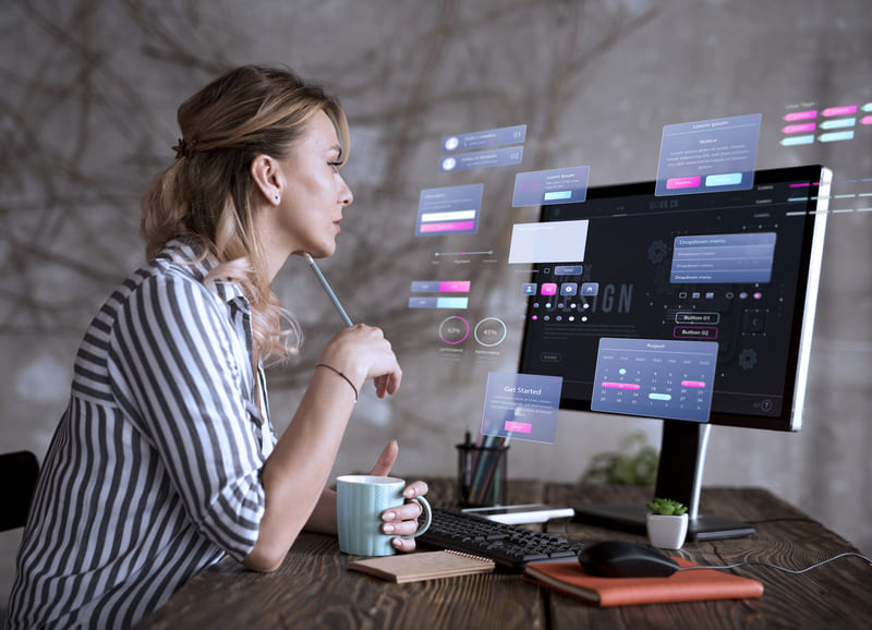 Diseñadora analizando una interfaz digital con elementos de experiencia de usuario en un monitor Hiweb