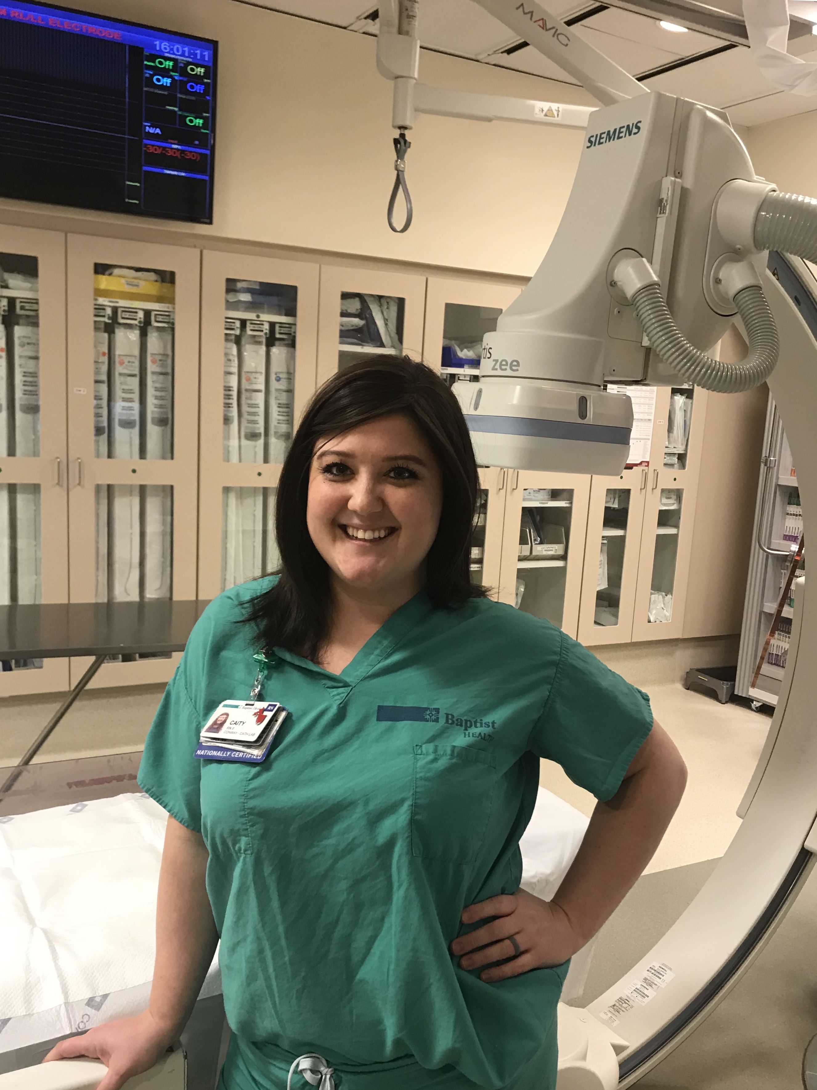 A female Baptist Health employee in a hospital room in front of healthcare machines