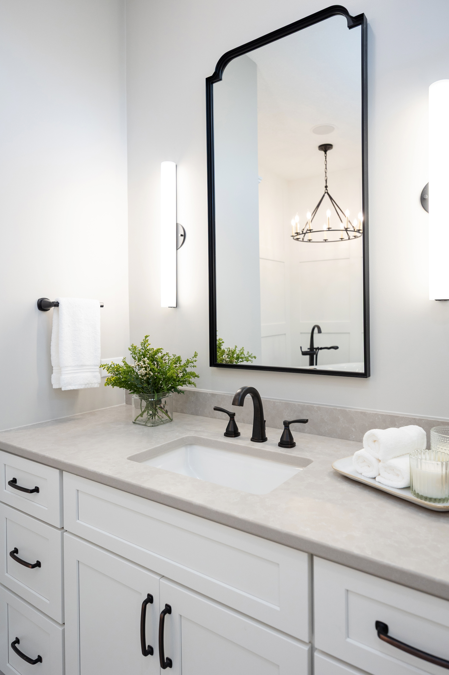 White bathroom vanity with taupe quartz counters and black fixtures. 