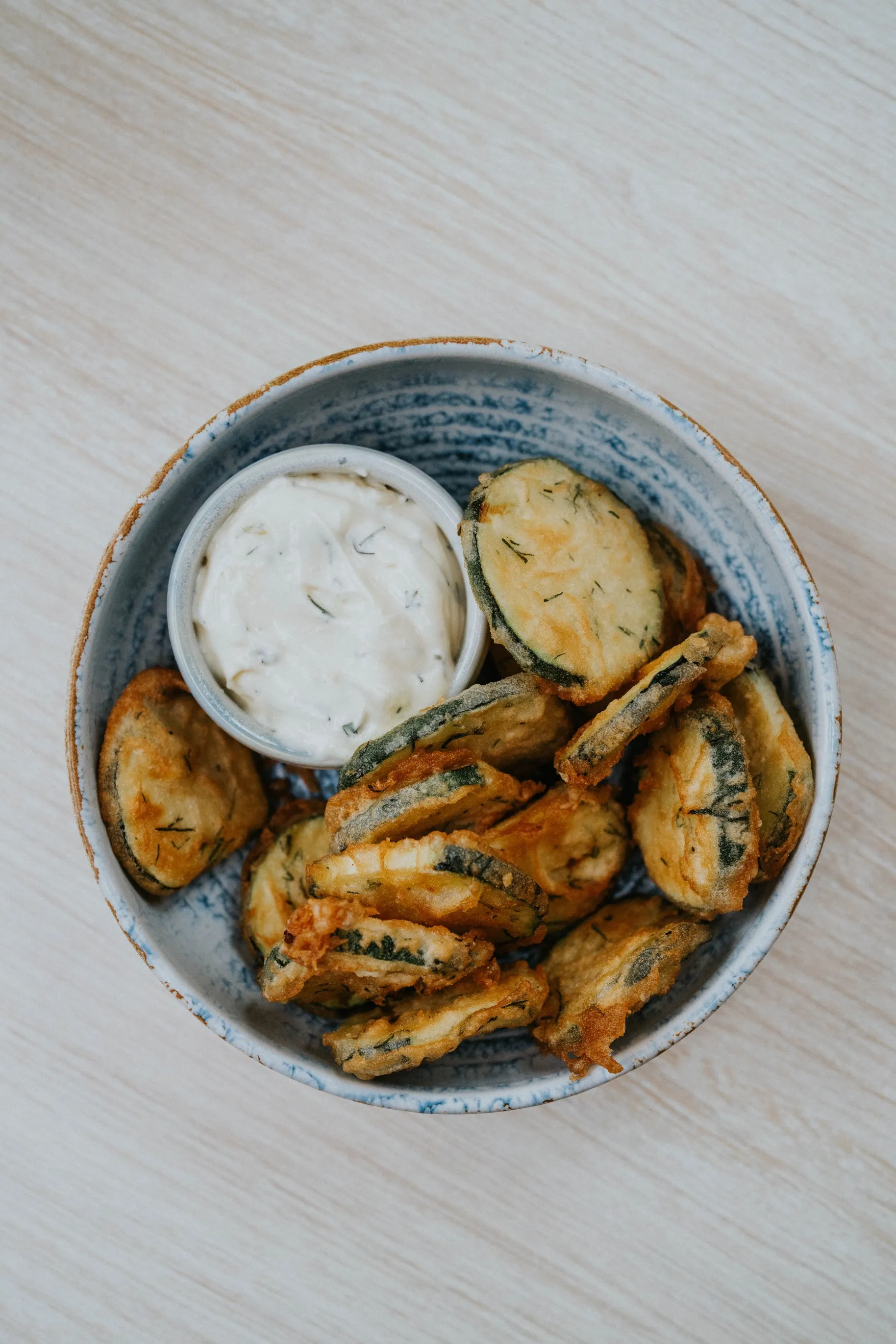 Crunchy fried zucchini chips served with a creamy dip.