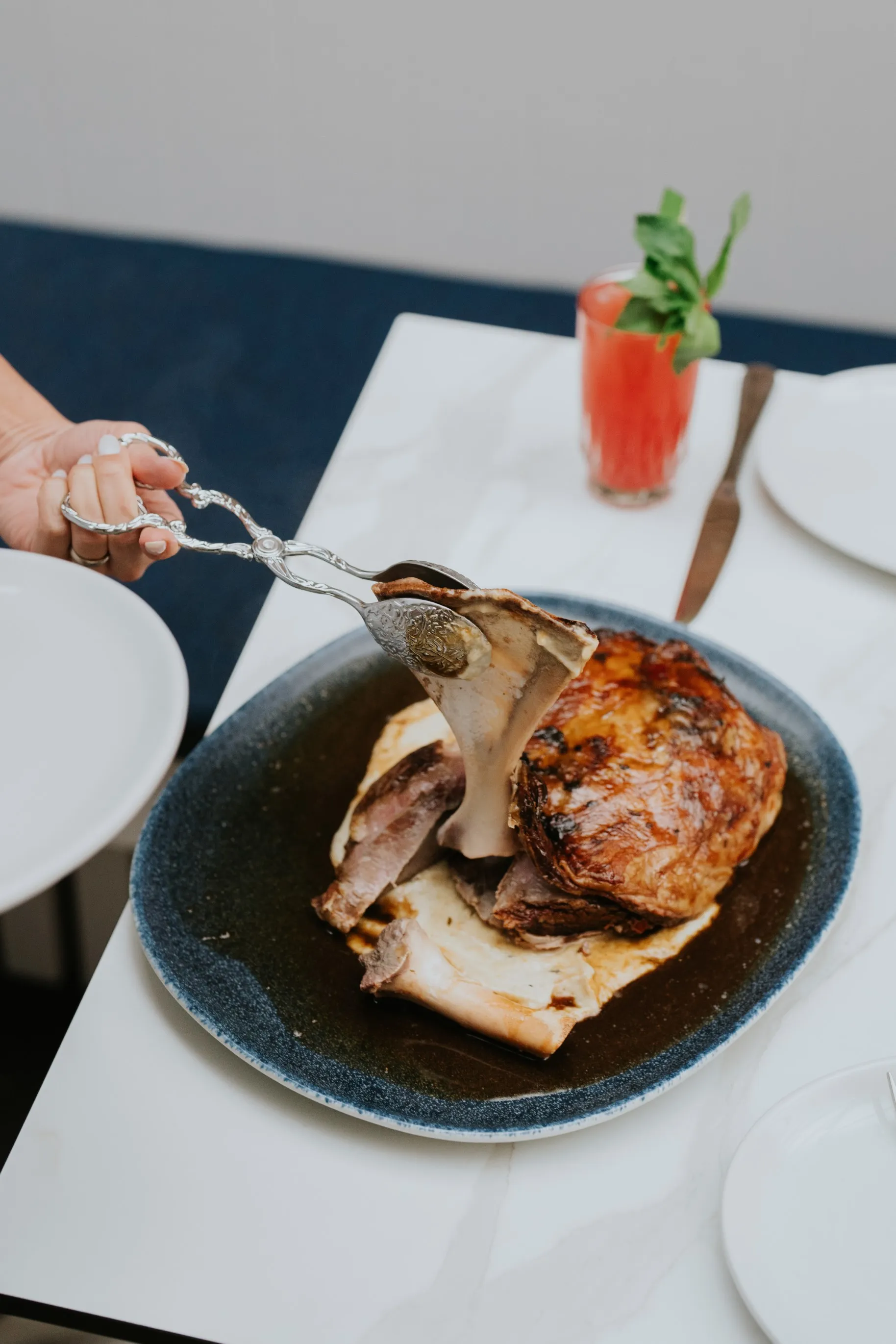 A person holding a clamp over a plate of food.