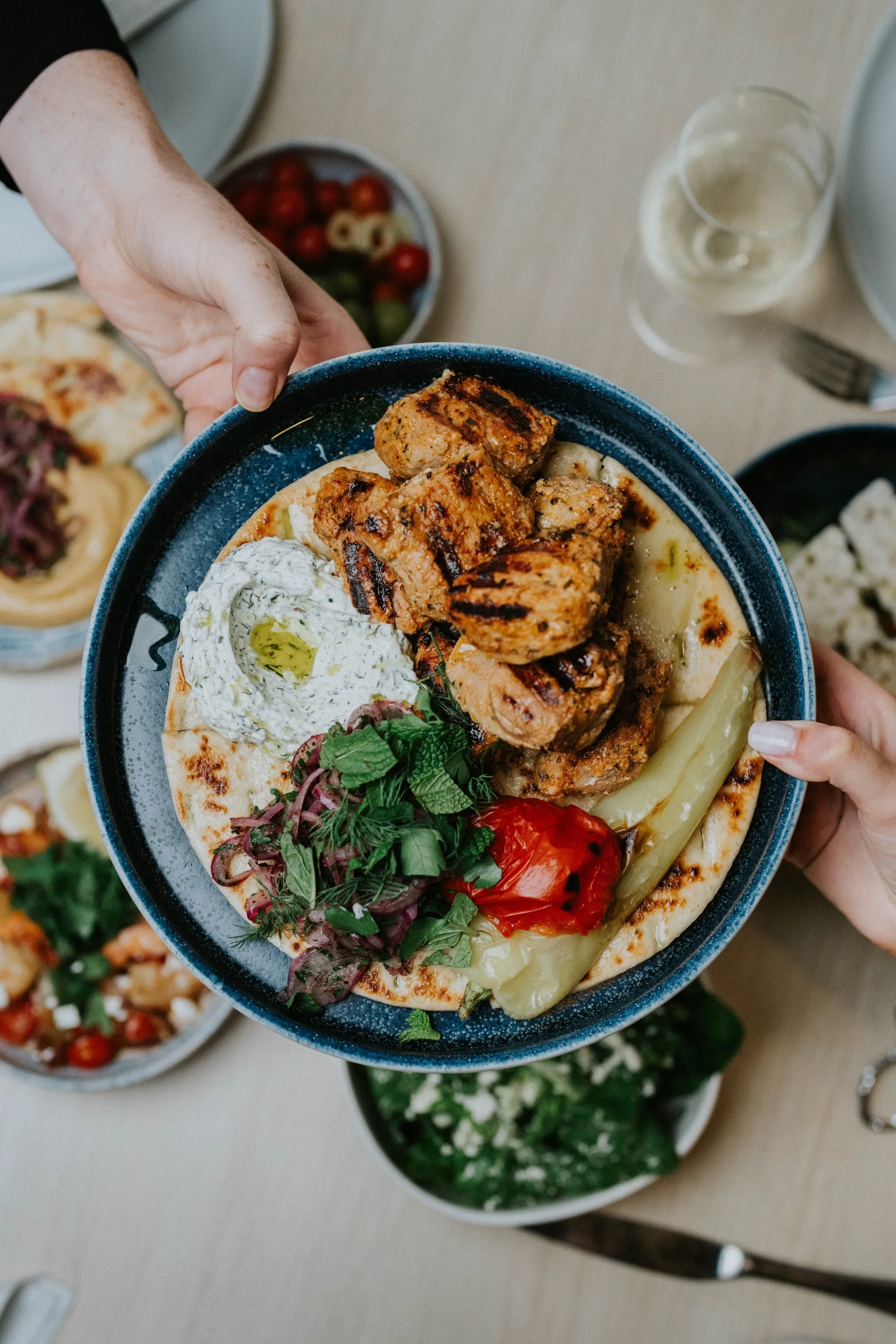 Two people holding a plate of food over a table, ready to enjoy a delicious meal.