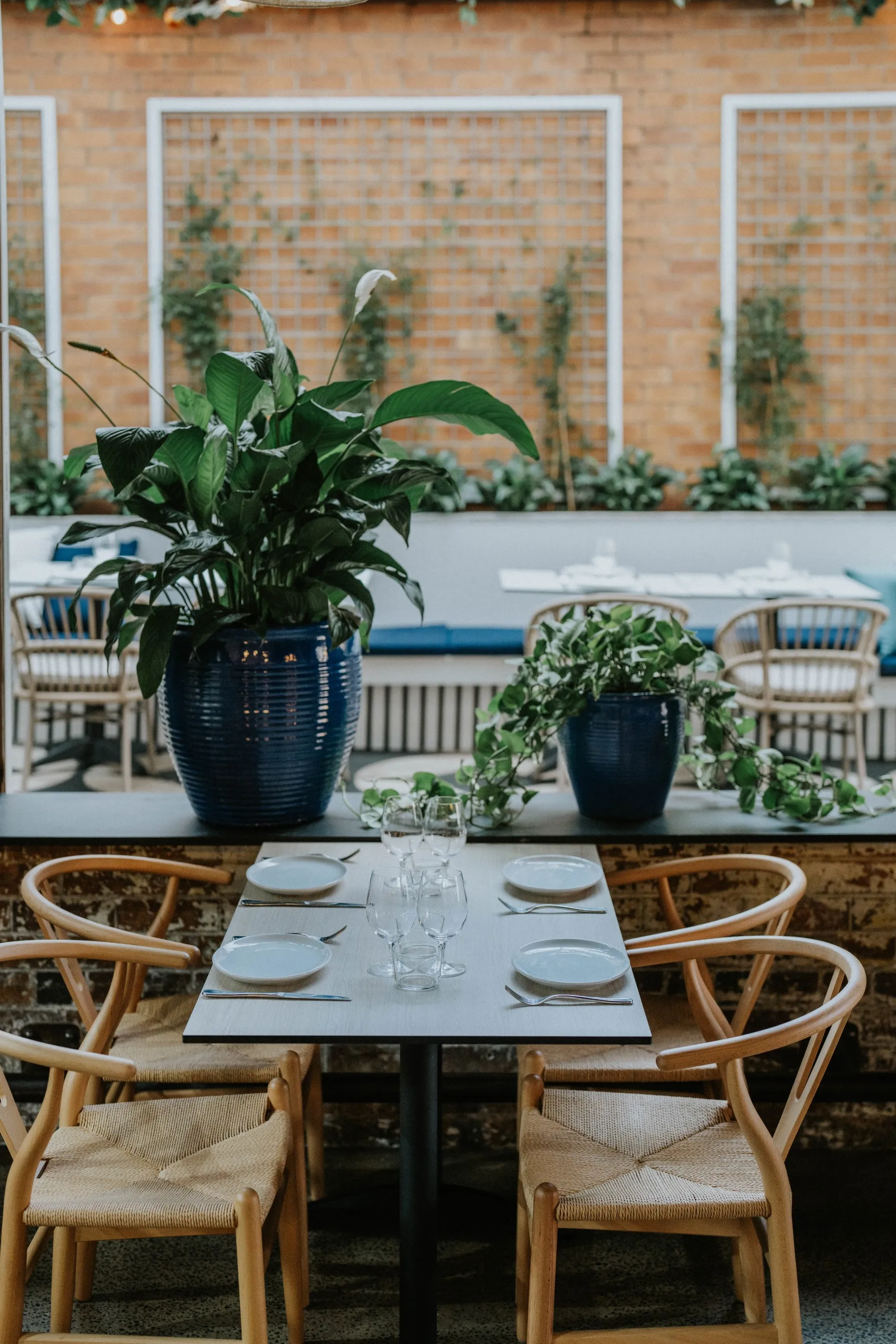 A table with blue vases and chairs in front of a brick wall, creating a stylish and modern outdoor seating area.