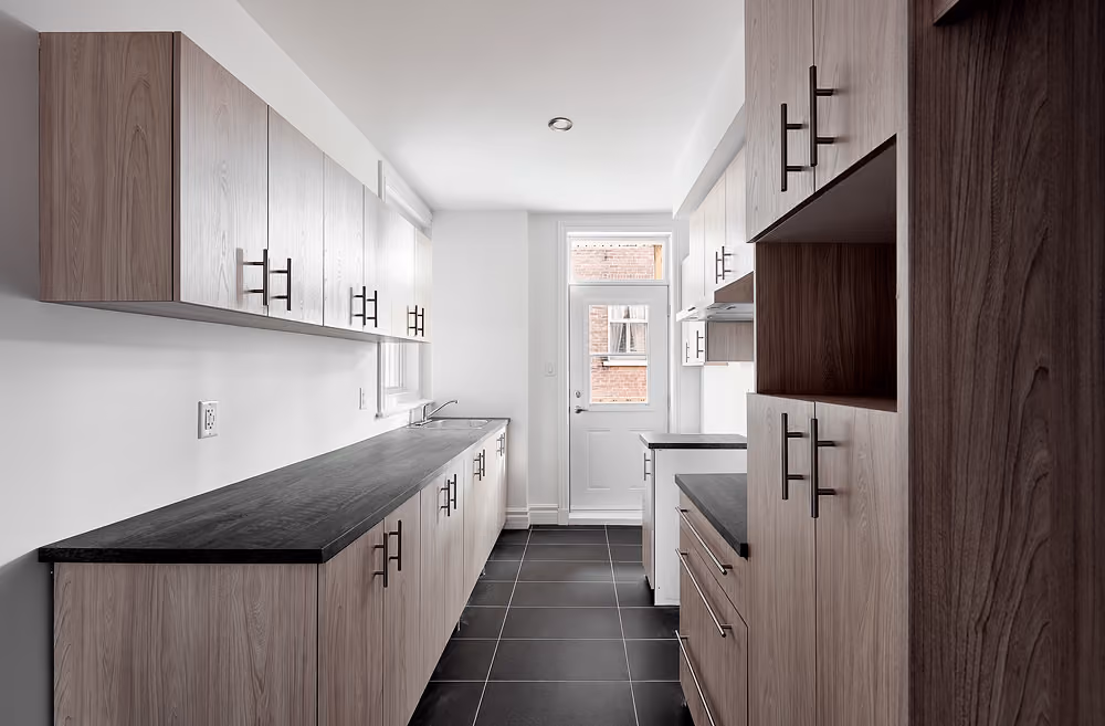 Cuisine rénovée avec armoires foncées dans un logement
