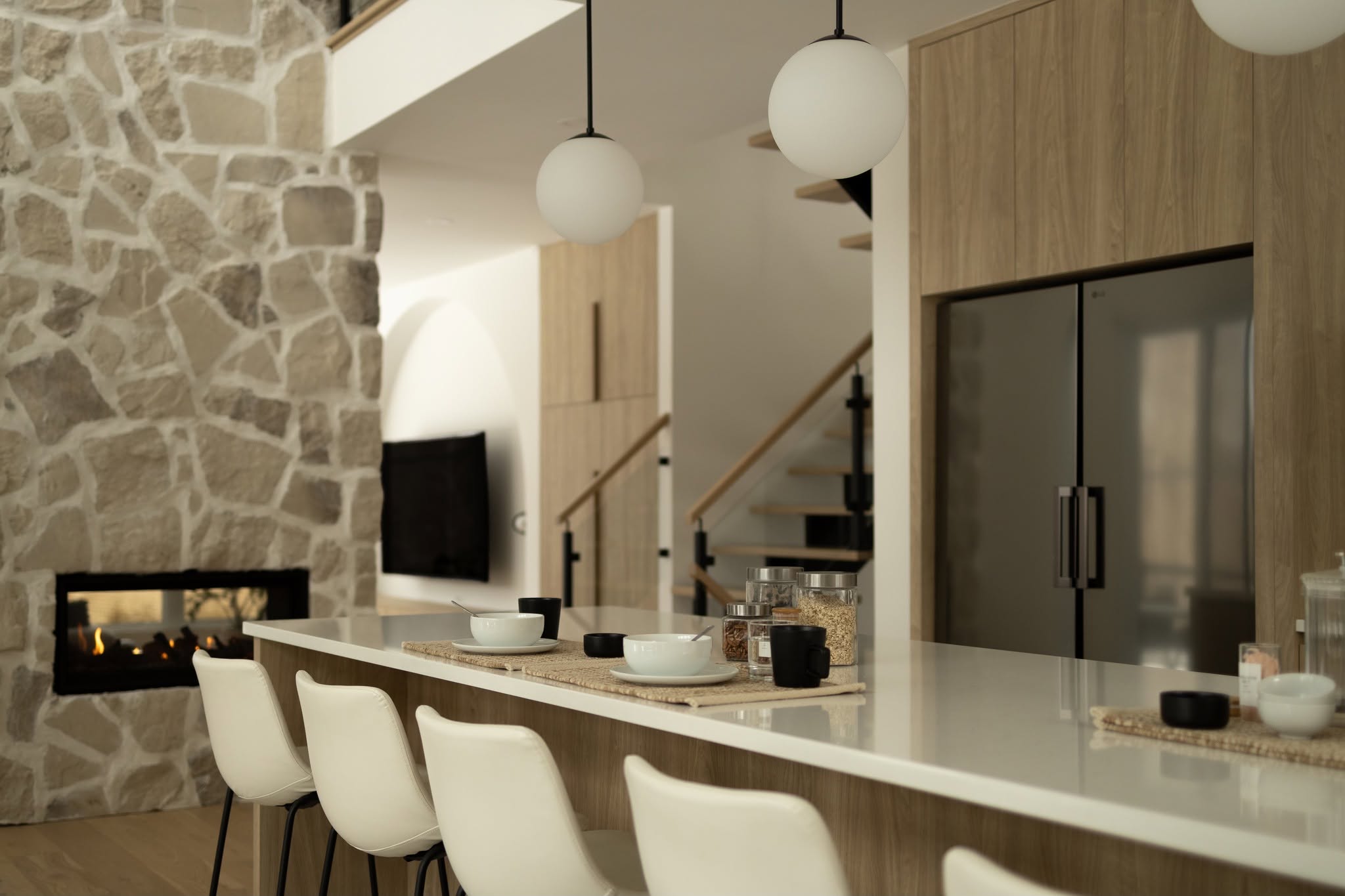 Îlot de cuisine et foyer dans un mur de pierre, maison neuve farmhouse à Stoneham