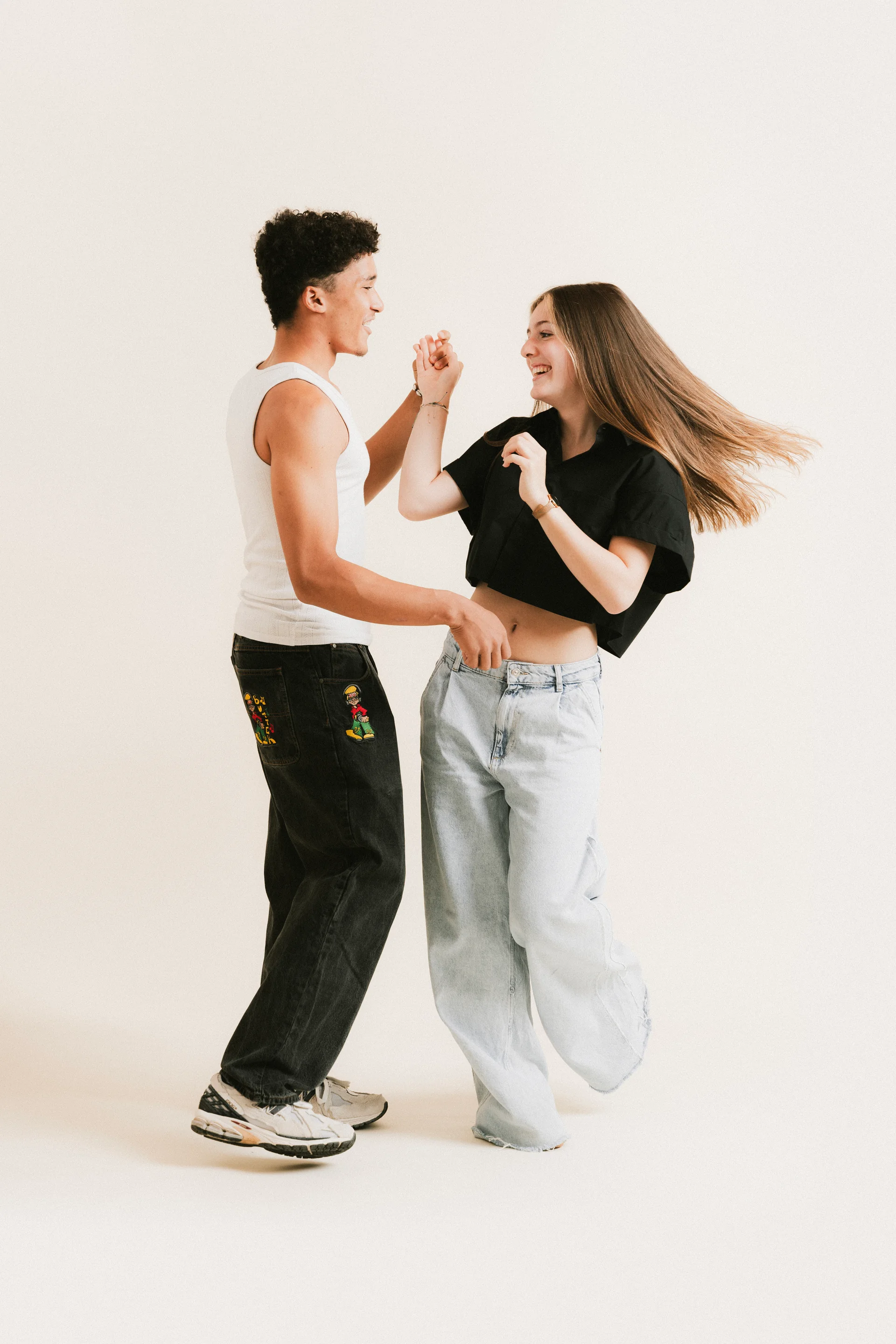 Lachendes jugendliches Tanzpaar in Jeans beim Kurs Bronze der Tanzschule Horn