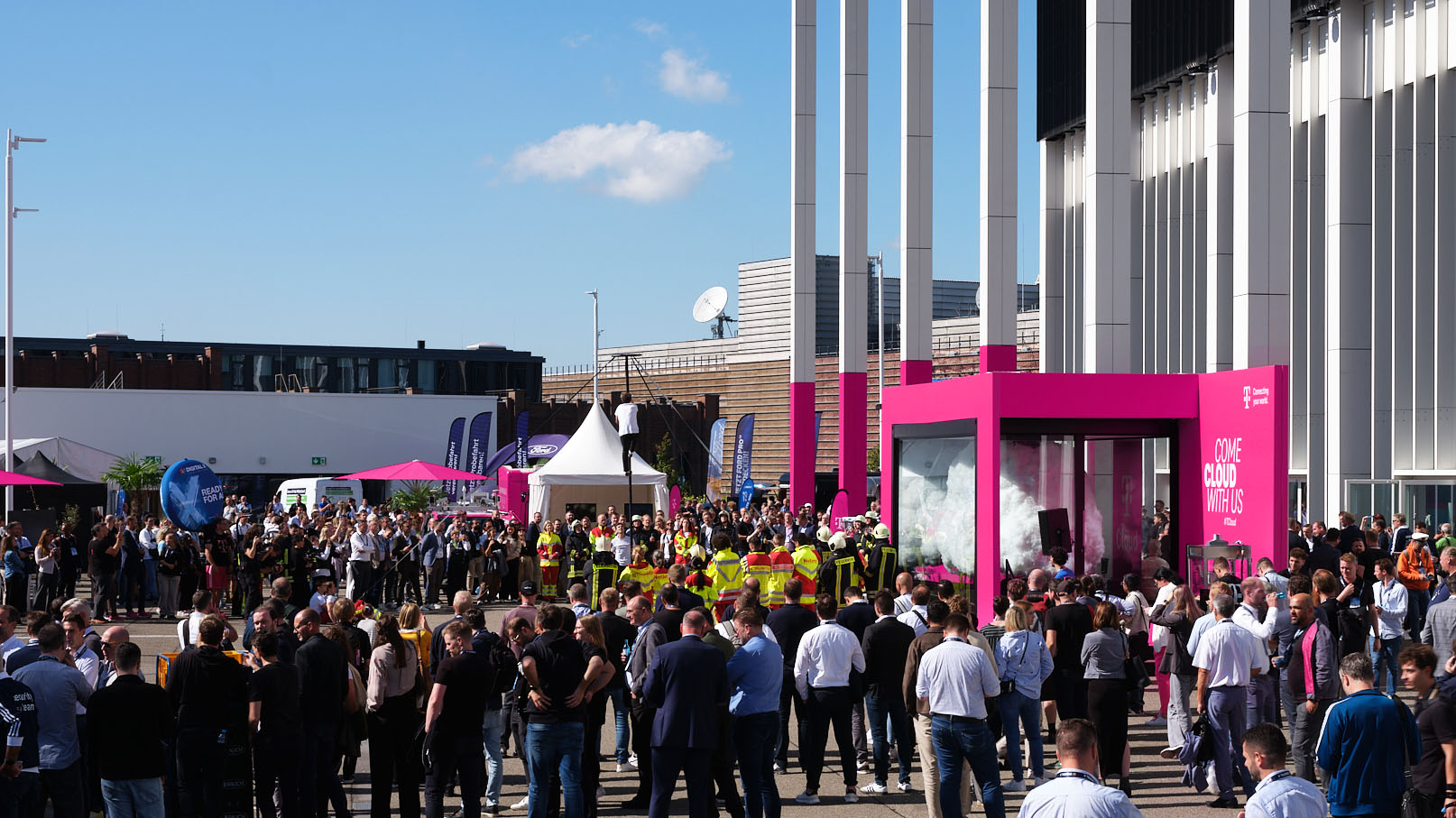 Menschenmenge vor der T Cloud von T‑Systems, die das leuchtende Kunstwerk im Stadtraum erlebt.