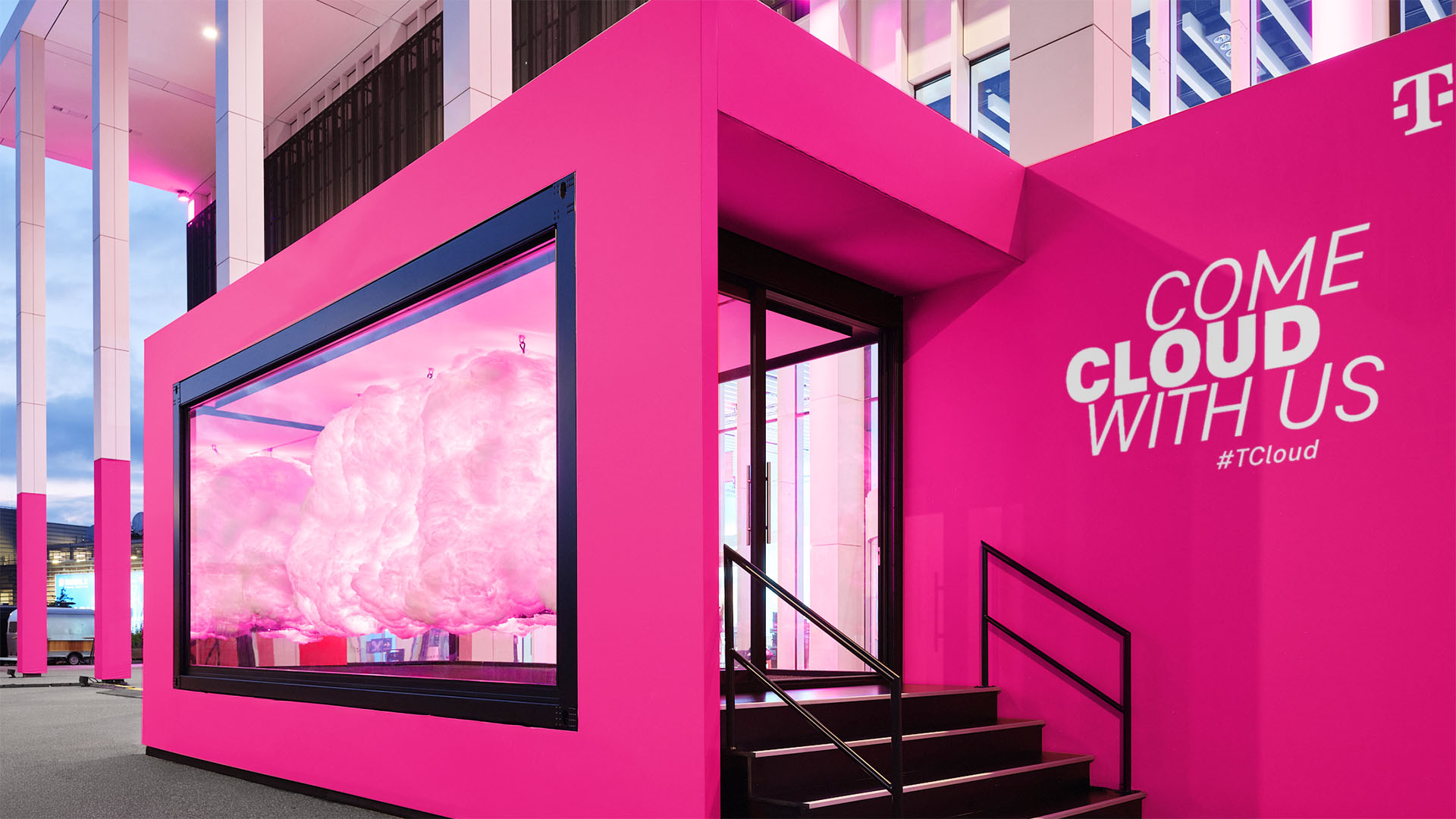 Außenansicht der T Cloud von T‑Systems mit leuchtenden Datenpunkten und reflektierenden Flächen im Stadtraum.