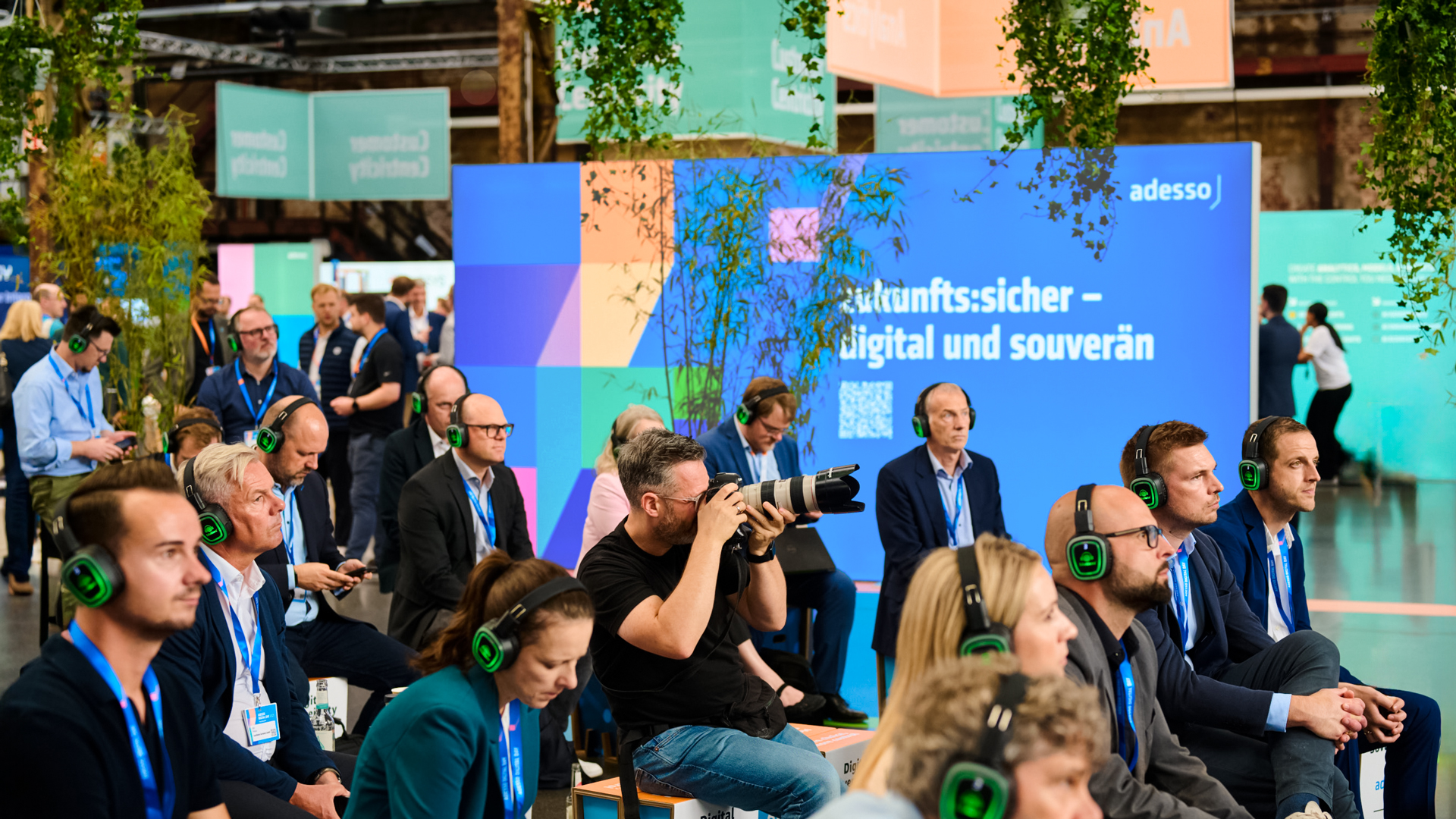 Teilnehmende mit Silent-Headsets verfolgen eine Session zum Thema „zukunfts:sicher – digital und souverän" beim Adesso Digital Day – Eventdesign und Stagedesign von Phocus Brand Contact.