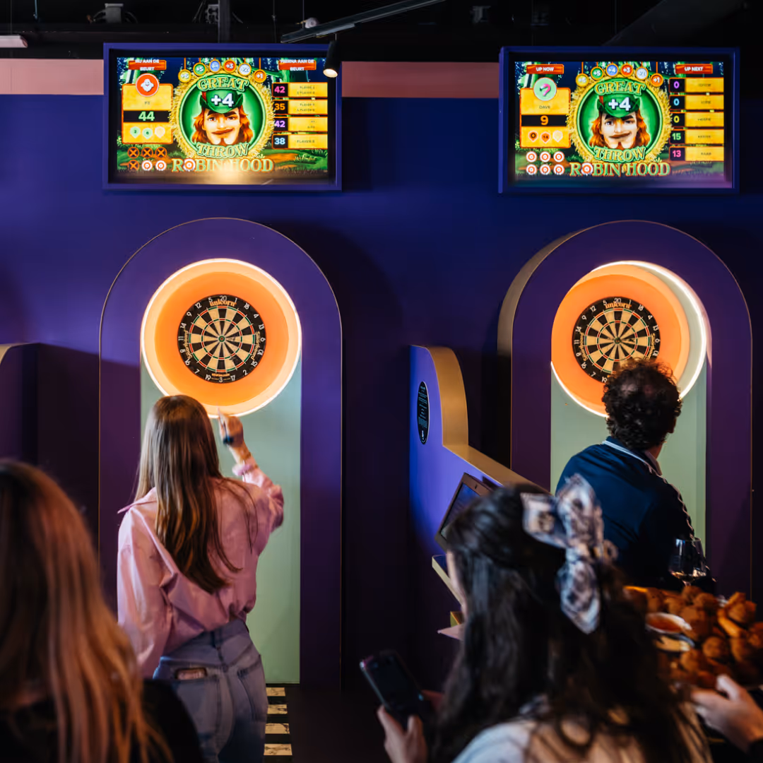 a group of people playing interactive darts on two different lanes.