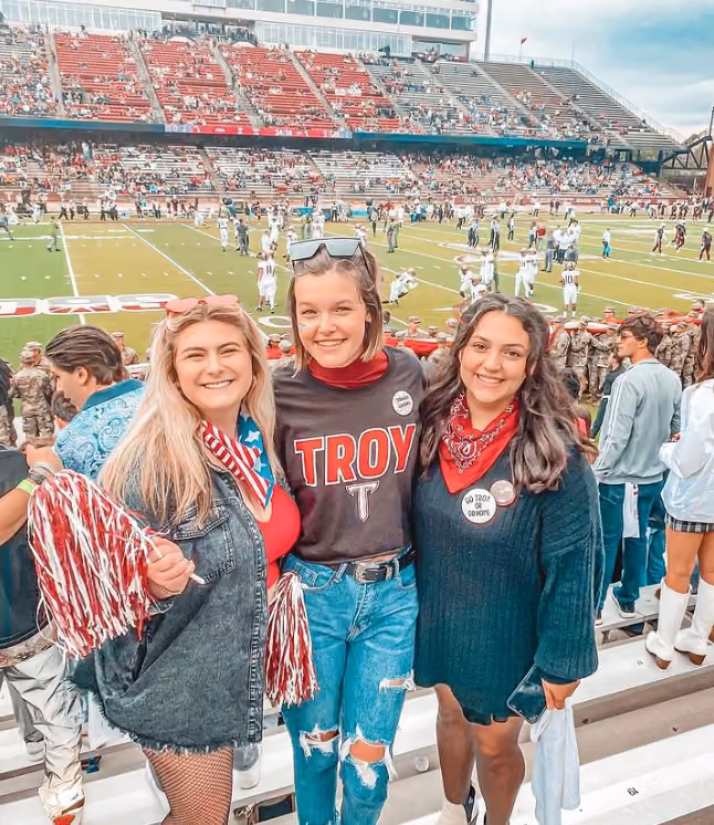 Three girls in Troy University gear at a game