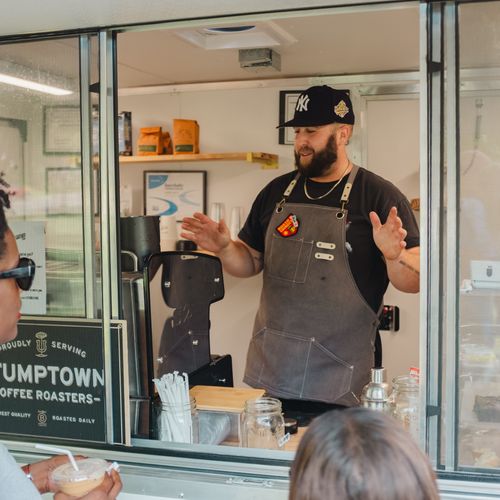 A man wearing an apron talking to a customer