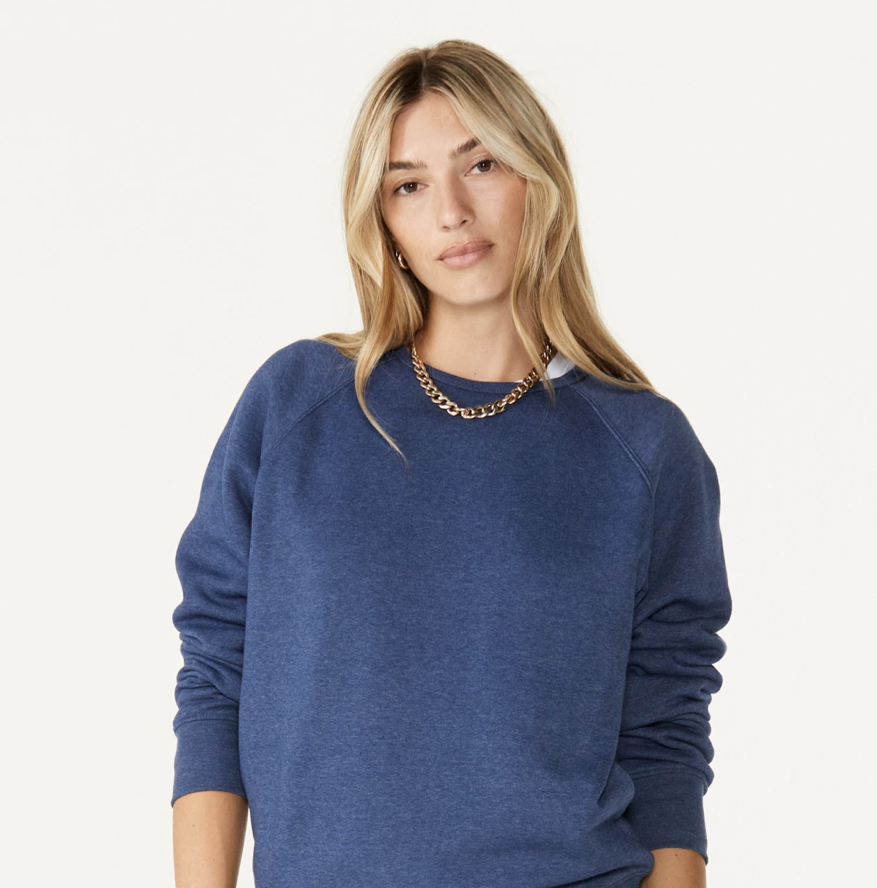 Woman wearing a Sportiqe blank blue sweatshirt with a gold necklace