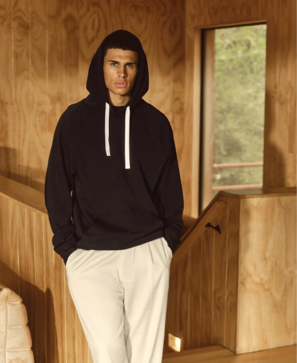 Man wearing a Sportiqe black hoodie in a cabin-like indoor environment