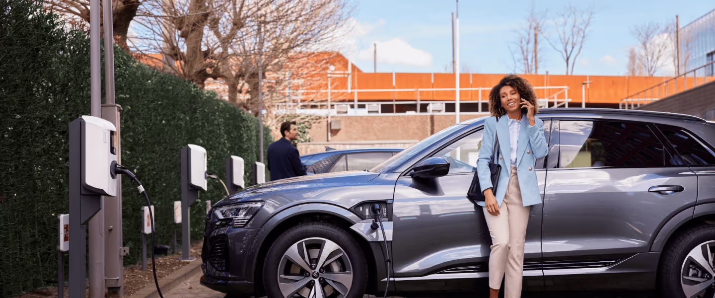 Vrouw die wacht tot haar auto is opgeladen aan een laadpaal.