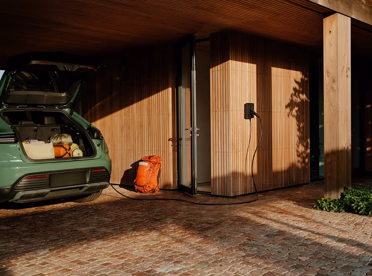 Elektrische auto laadt op onder een carport met wandlader naast de muur.