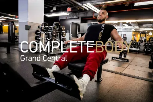 Man in red pants exercises on rowing machine in gym with dumbbells and mirrors nearby.