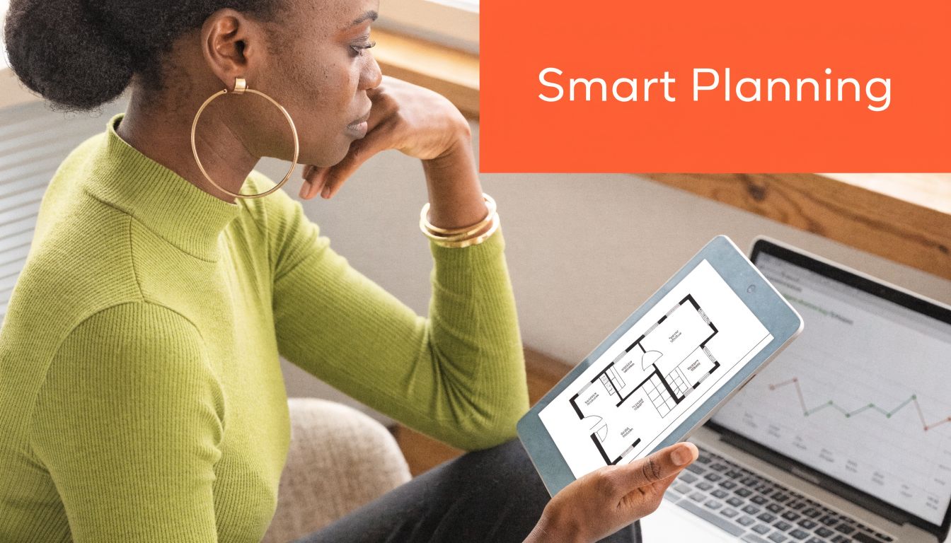 A woman reviewing a house floor plan on a tablet while working on a laptop computer.