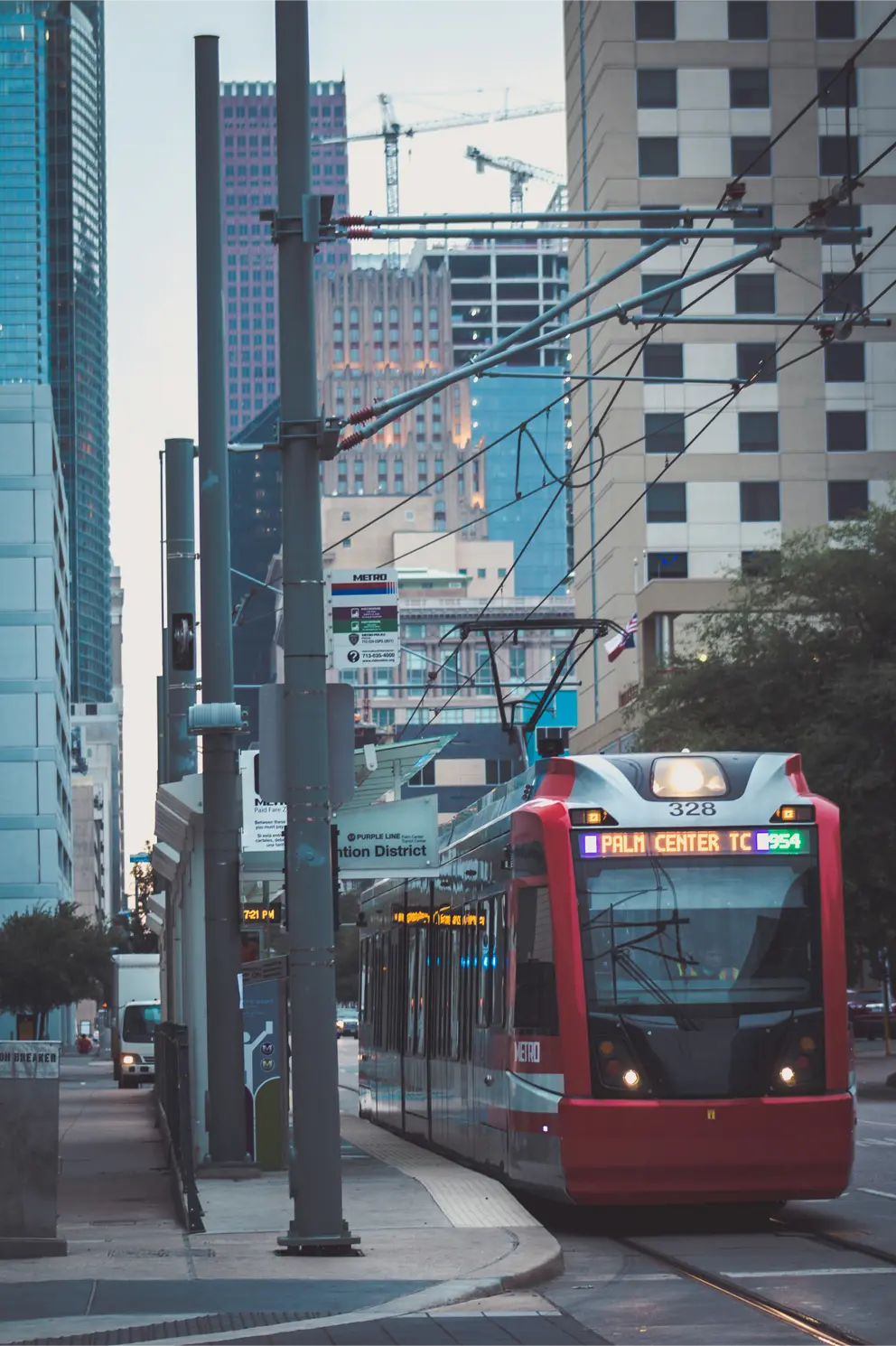 A photograph of a red metro train in downtown Houston.